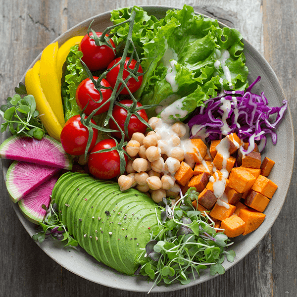Healthy looking salad bowl with many fresh items and salad dressing